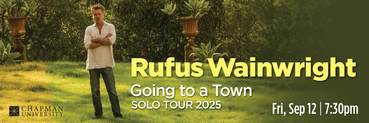 A photograph of Rufus Wainright standing on a lawn.